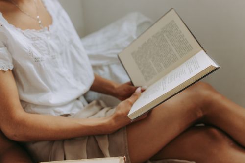Free A woman in casual attire enjoys a quiet moment reading a book indoors. Stock Photo