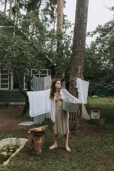 一位白人妇女在乡村住宅旁的绿地上晾衣服