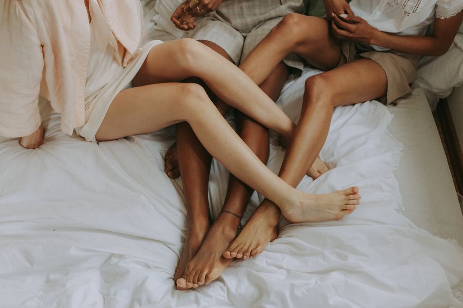 세 명의 여성이 침대 위에서 느긋하게 포옹하며 연결의 상징을 나타내고 있습니다.