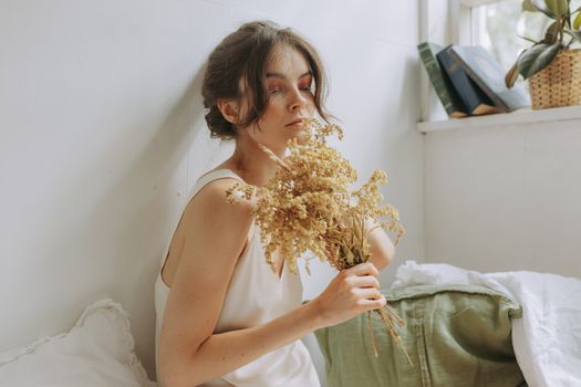 这幅安静的肖像描绘了一位在舒适房间里手持干花的女人