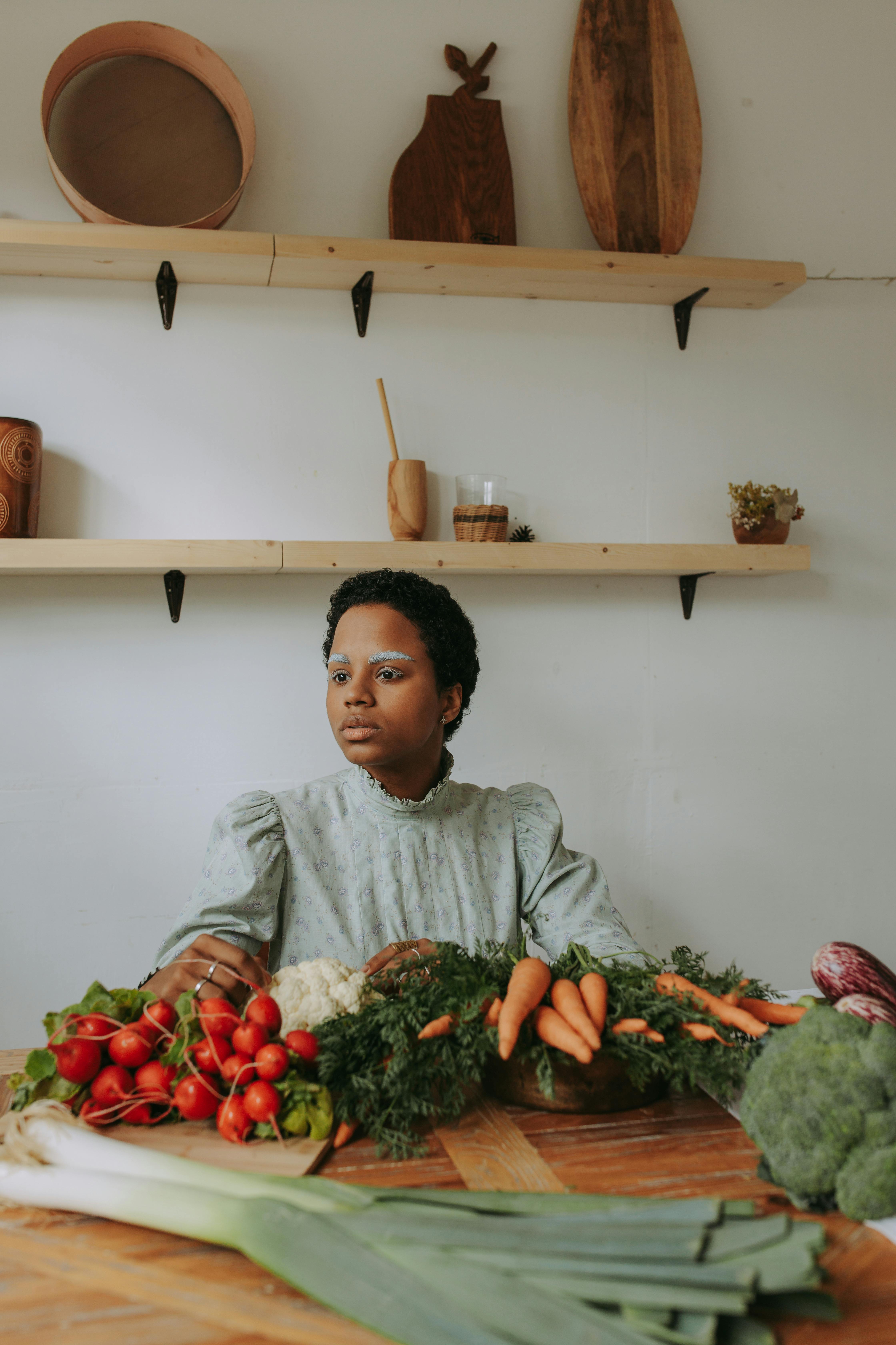 woman in gray long sleeve shirt holding green vegetable