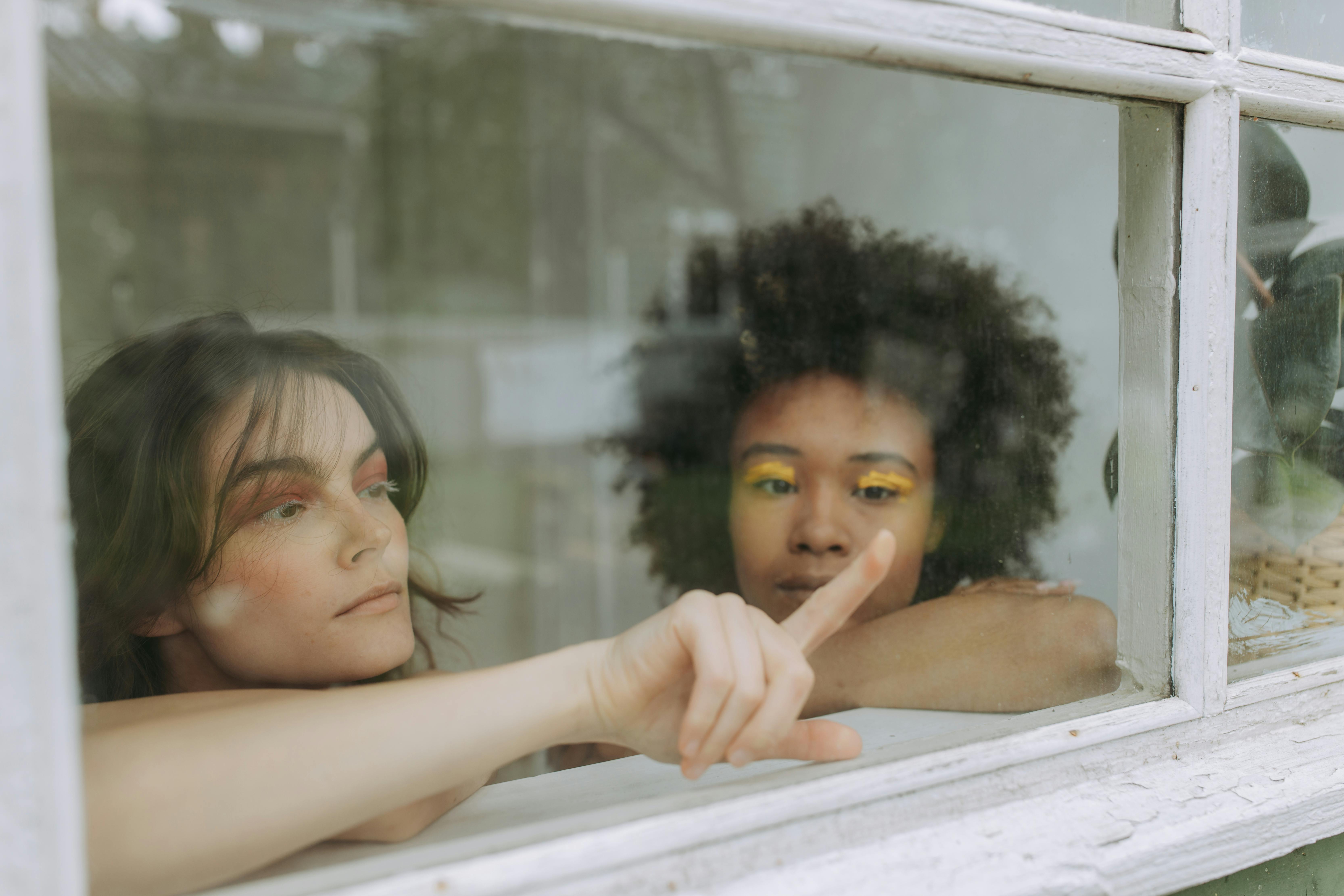 woman in white tank top leaning on glass window