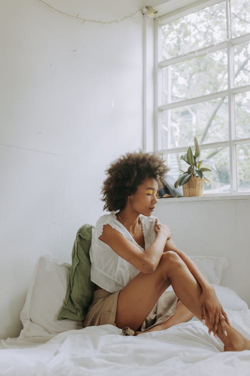 Woman with Afro Hair Sitting on Bed