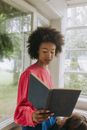 Woman in Red and White Shirt Holding Black Book