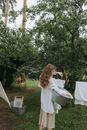 Woman in White Long Sleeve Shirt Standing Near Green Trees