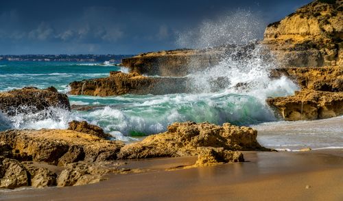 Free Dynamic scene of waves crashing onto a rugged rocky shore with a stormy sky above. Stock Photo