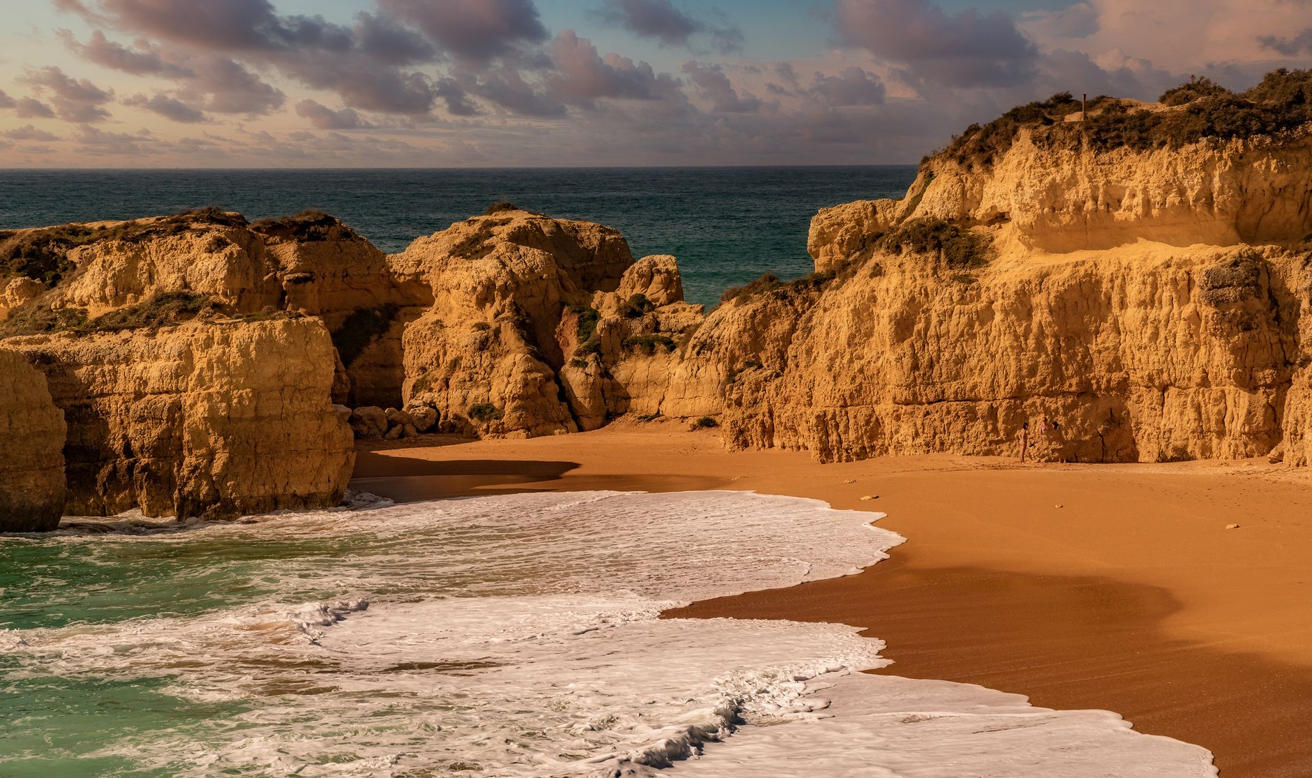 Experience the beauty of golden cliffs meeting the serene ocean waves at sunset. Perfect coastal tranquility.