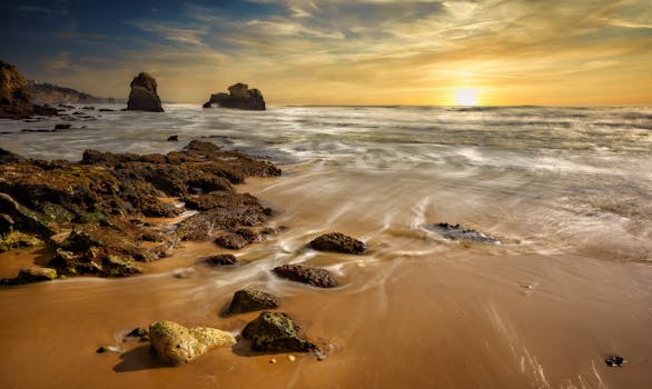 Beautiful sunset at a rocky seascape beach with gentle waves and a moody sky.