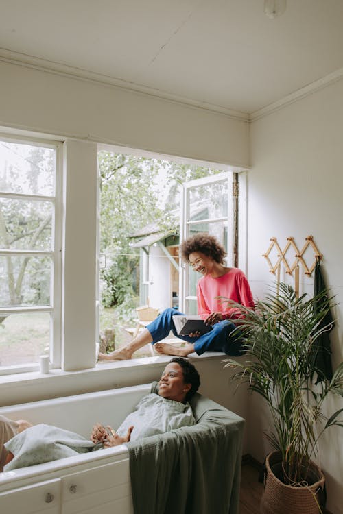 Woman in Red Long Sleeve Shirt Sitting on White Bed