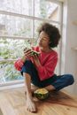 Woman in Red Crew Neck T-shirt and Blue Denim Jeans Sitting on Brown Wooden Table