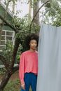 Woman in Red Long Sleeve Shirt Standing Beside White Curtain
