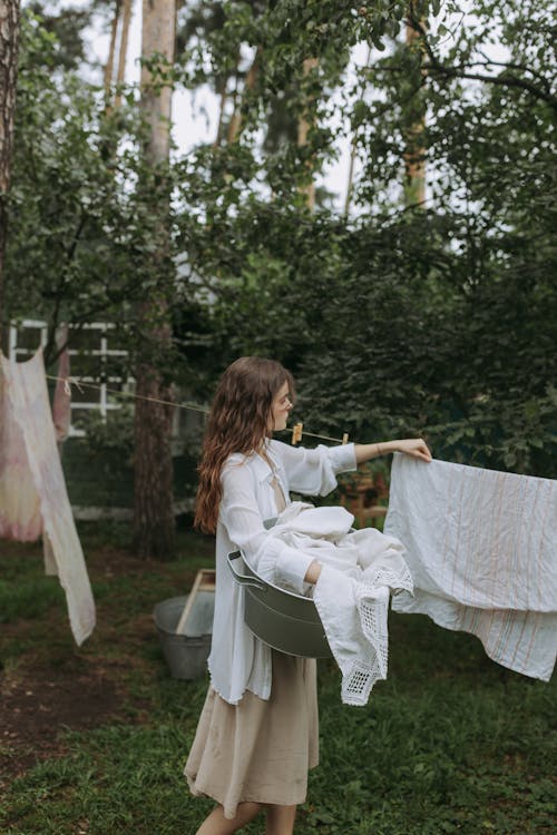 Woman in White Long Sleeve Shirt Sitting on White Plastic Chair