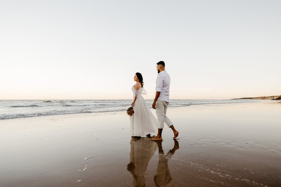 Romantic newlyweds walking on sandy beach at sundown