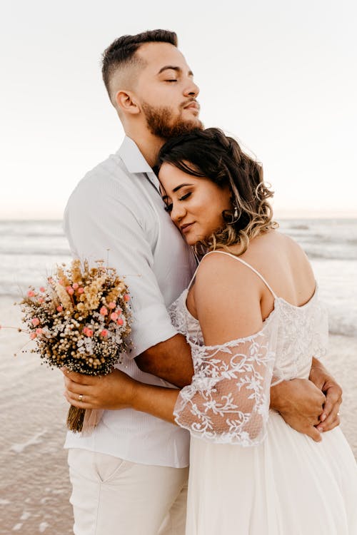 Newlywed couple embracing on beach