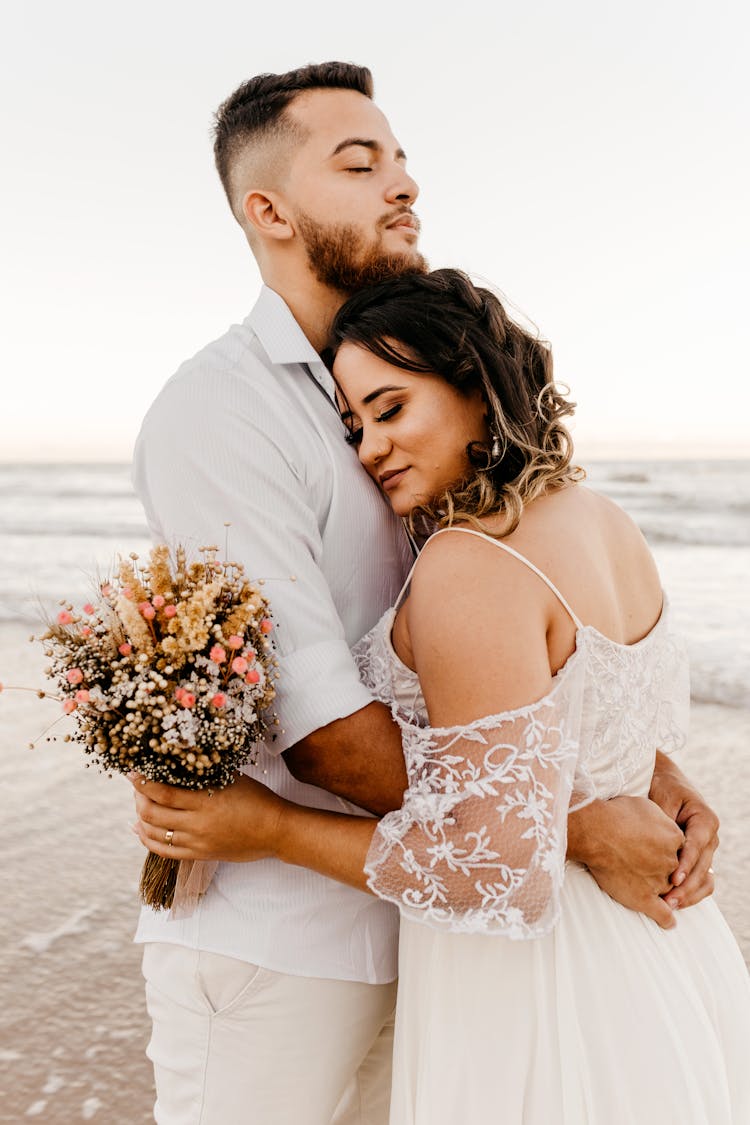 Newlywed Couple Embracing On Beach