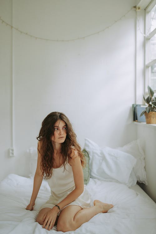 Free A Woman Wearing Sleepwear Sitting on Bed Stock Photo