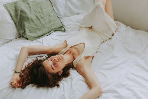 Free A woman lying on bed in a relaxed pose, showcasing comfort and tranquility. Stock Photo