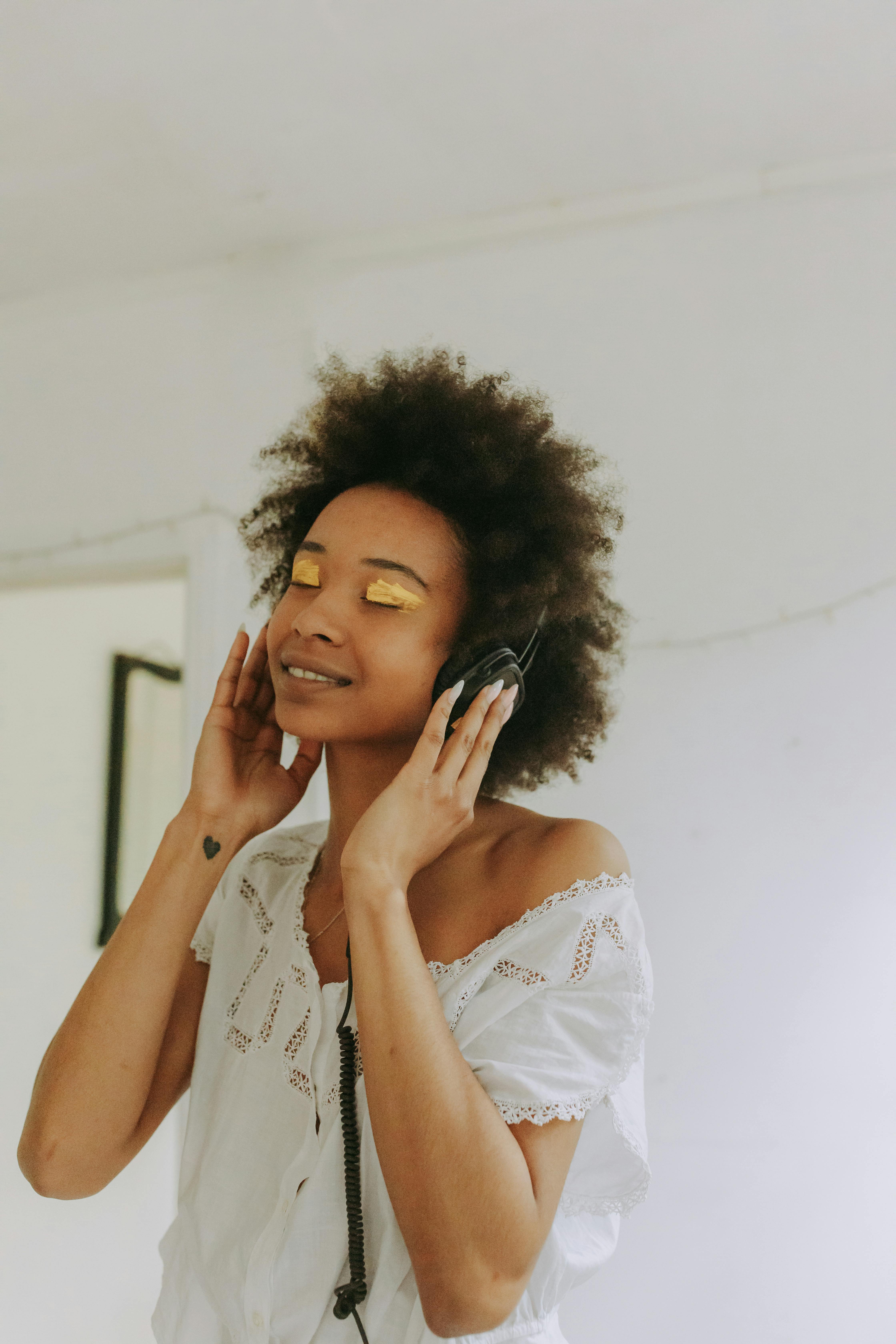 a woman in white top listening on a headphone