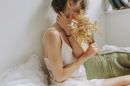Woman in White Tank Top Holding Yellow Flowers