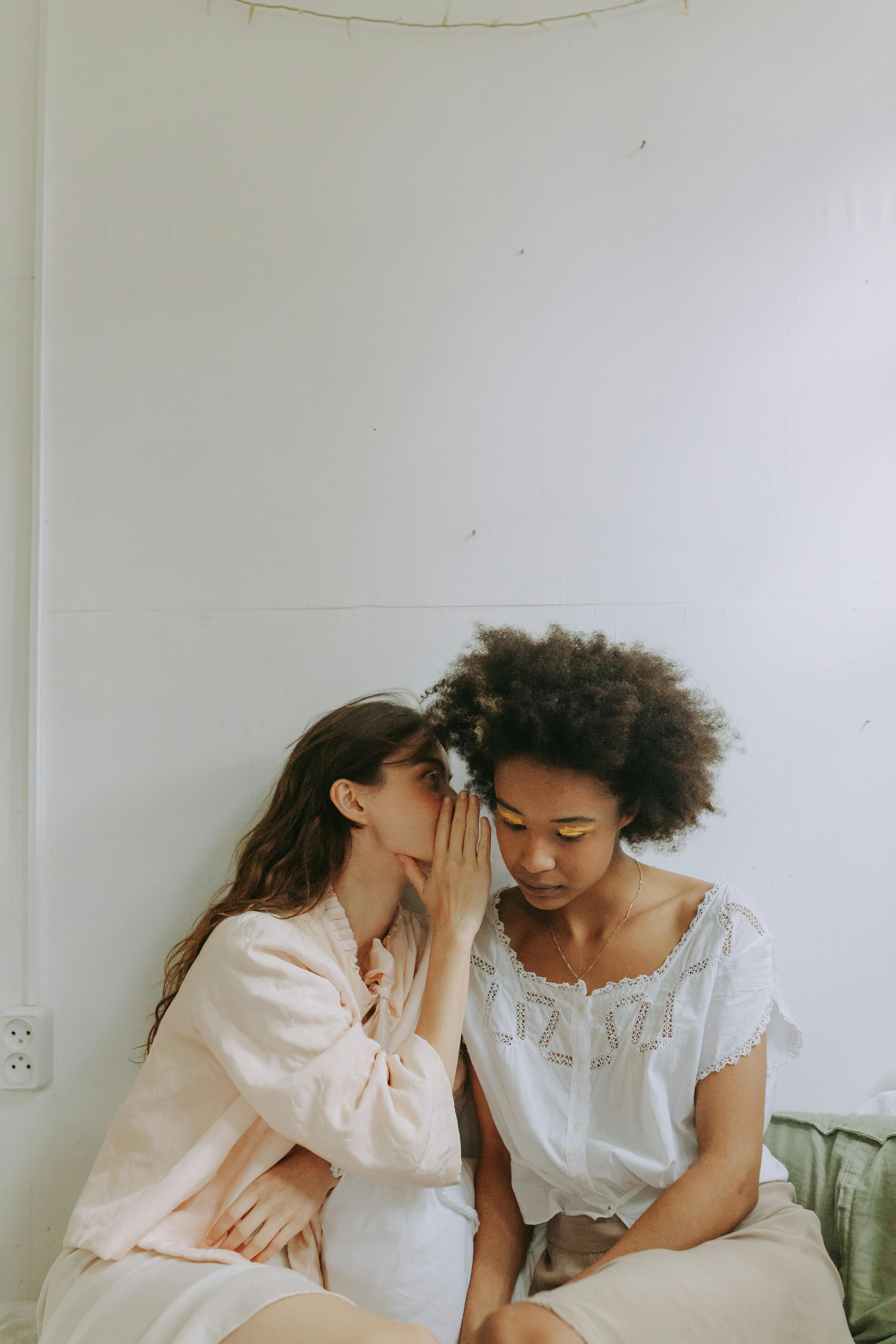 person whispering near the woman s ear