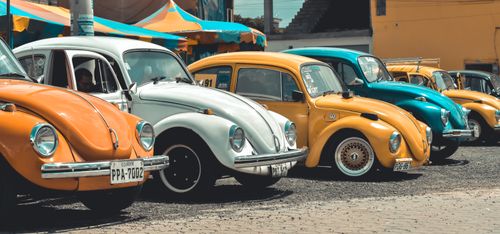 Free A collection of colorful vintage Volkswagen Beetles parked outdoors, showcasing classic automotive design. Stock Photo