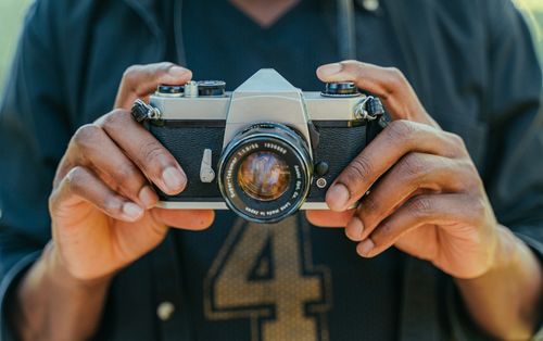 Free Close-up image of hands holding a vintage camera outdoors, emphasizing photography art. Stock Photo