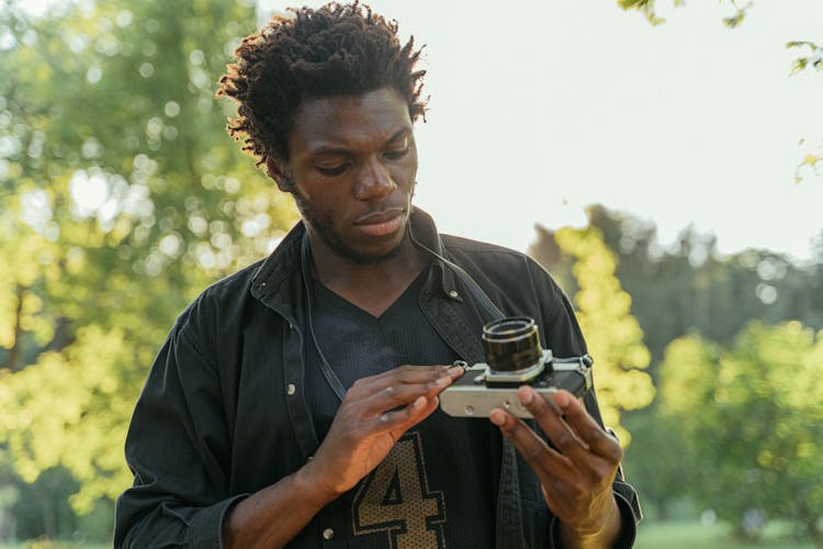 Man Staring At His Black And Silver Dslr Camera