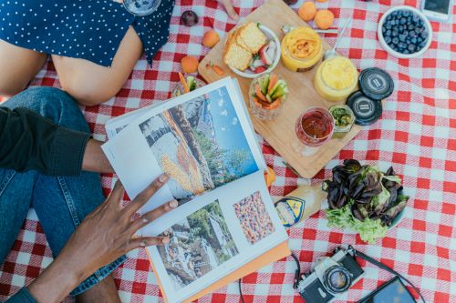 Free A vibrant outdoor picnic featuring diverse food, a magazine, and a relaxed atmosphere. Stock Photo