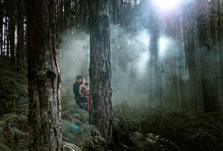 Young Couple Hugging In Mysterious Forest