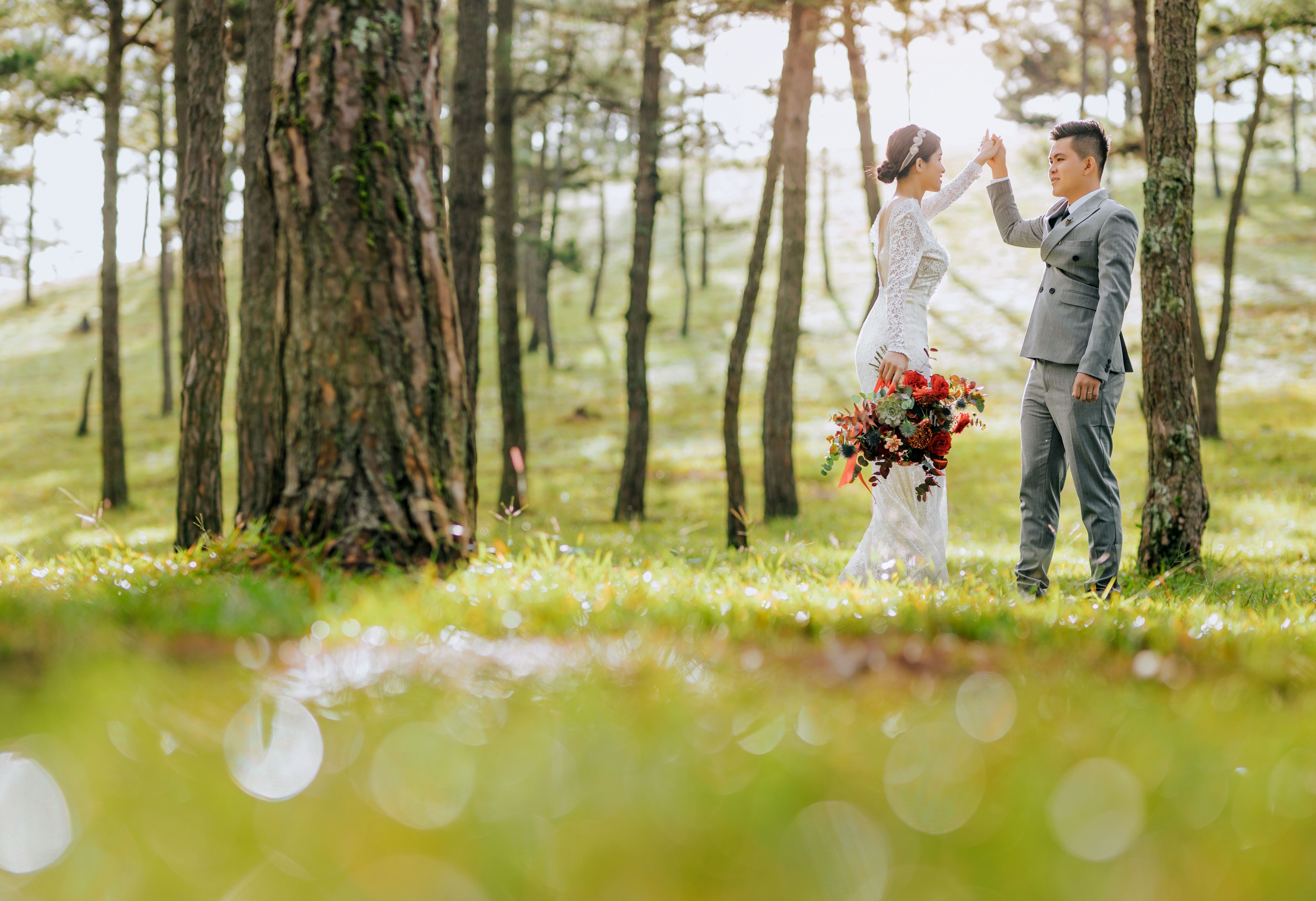 Happy cheerful Asian couple holding hands in forest · Free Stock Photo