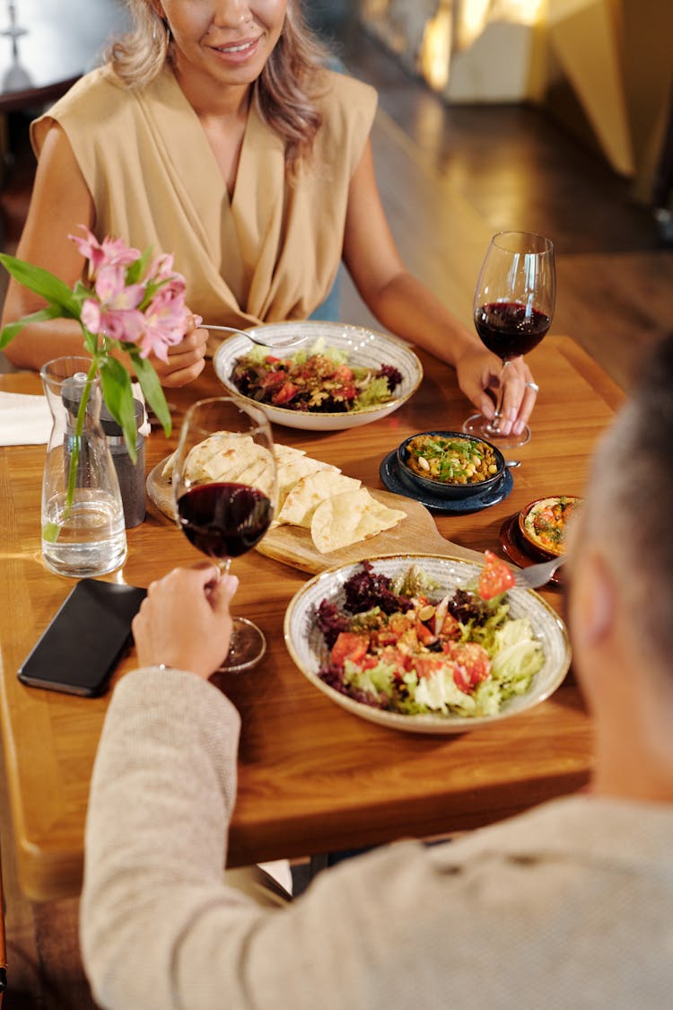 A Couple Dating While Holding A Glass Of Wine On The Table