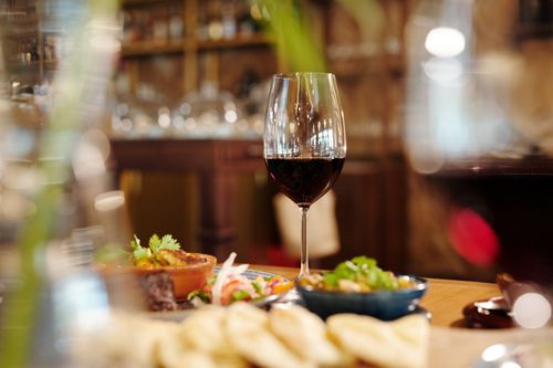 Free Close-up of a red wine glass amidst a variety of appetizing dishes on a restaurant table. Stock Photo