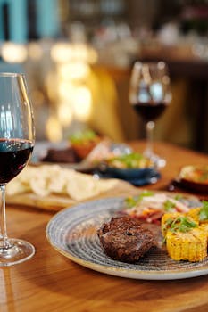 A gourmet steak dinner served with wine in a restaurant setting, capturing an elegant dining experience.