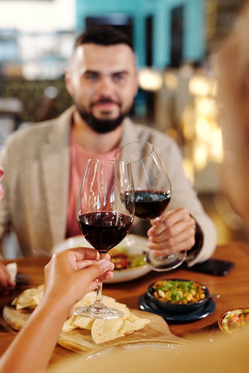 Free Two people clinking glasses of red wine at a festive dinner gathering, capturing a moment of celebration. Stock Photo