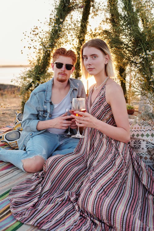 Couple Sitting on a Picnic Blanket and Drinking Wine