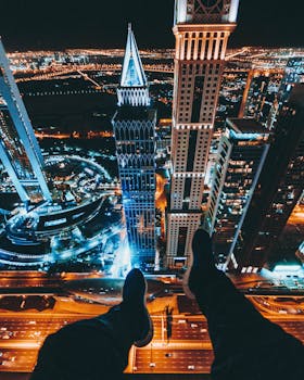 High-angle view of Downtown Dubai skyscrapers at night with illuminated urban landscape and streetlights.