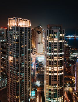 A breathtaking aerial view of illuminated skyscrapers at night overlooking the cityscape.
