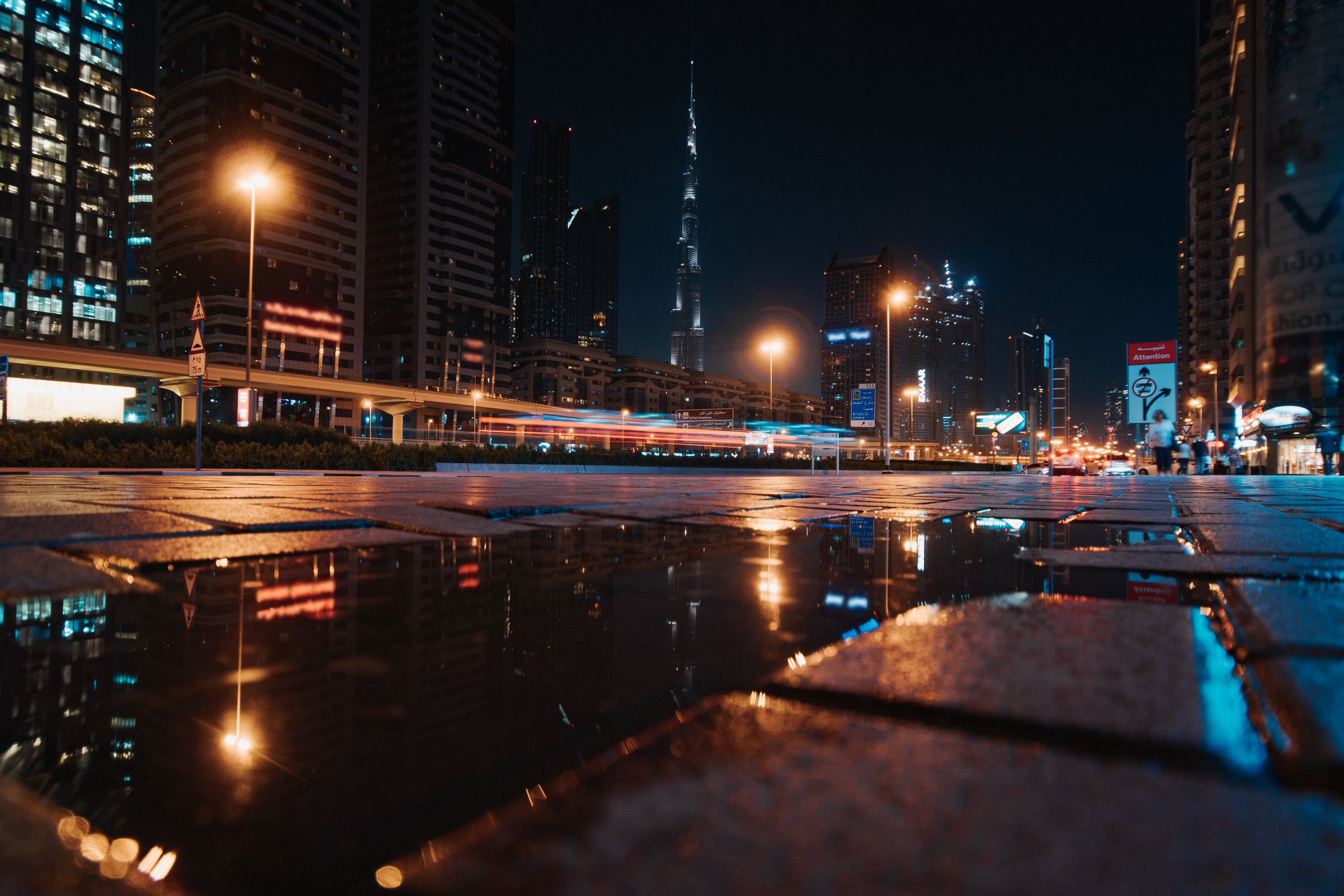 A stunning nighttime cityscape of Dubai featuring the illuminated Burj Khalifa and urban reflections