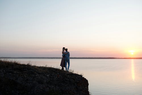 Free A Romantic Couple Hugging Each Other while Watching Sunset Stock Photo