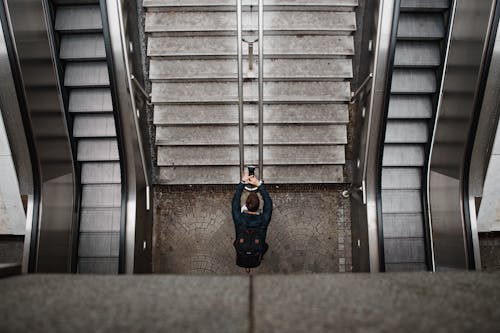 Человек в синем пиджаке и черных штанах идет по серой лестнице