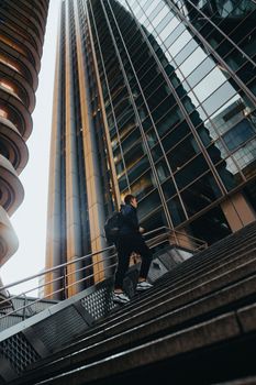 一位商人爬上现代城市景观中由高大的反光摩天大楼构成的混凝土楼梯