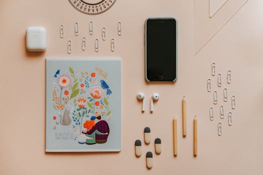 A neatly arranged flat lay of stationery items and gadgets on a pastel surface.