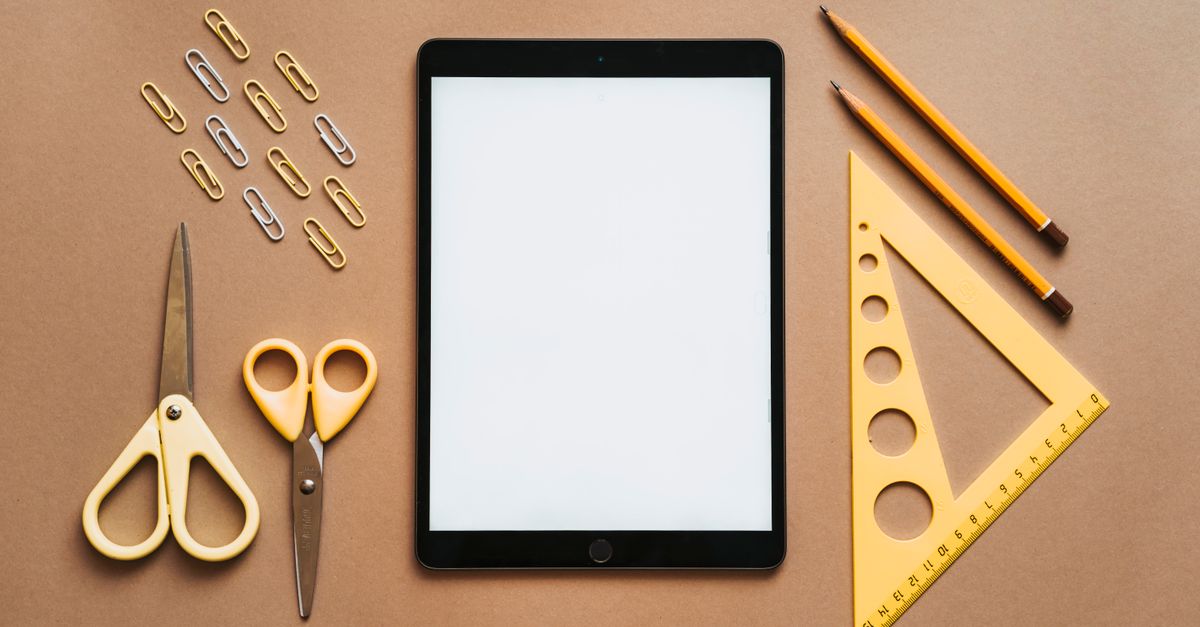 Stationery arranged with tablet on brown background.