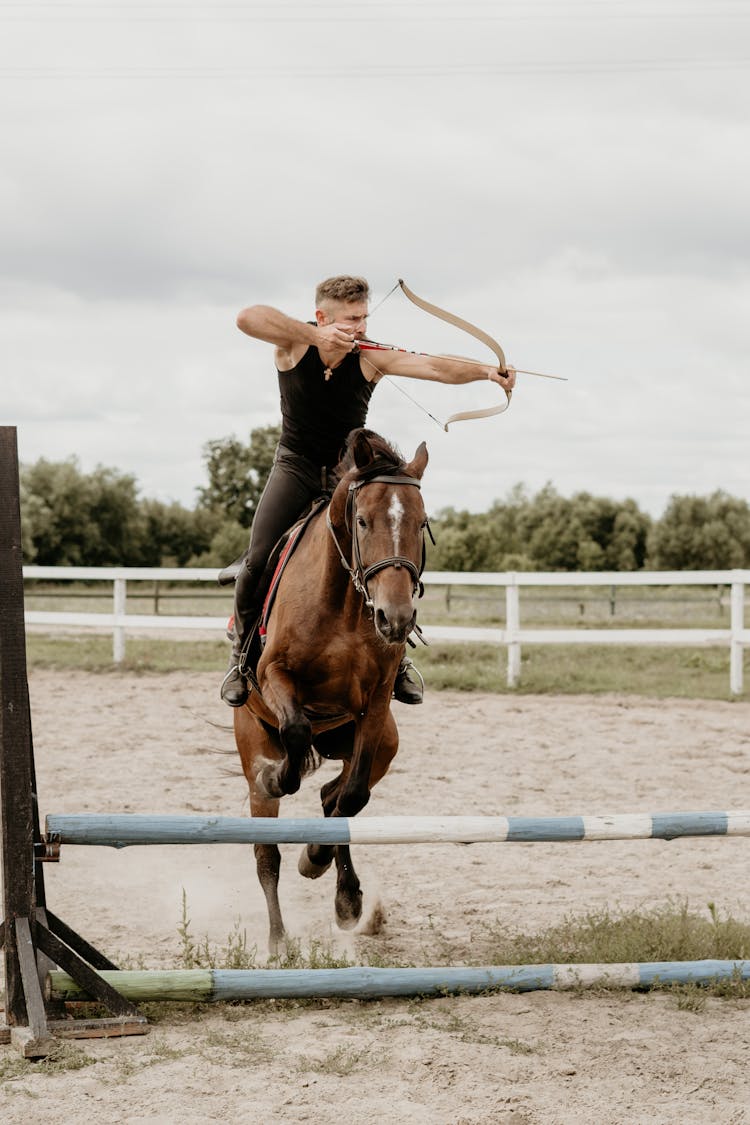 A Man Shooting An Arrow While Riding A Horse