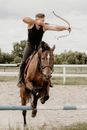 Man Shooting Bow from Horse Jumping over Hurdle