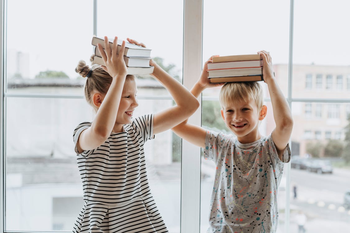 Free Brother and Sister With Books on Their Heads Stock Photo