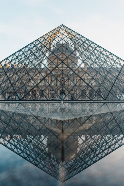 The Louvre Pyramid reflecting in the water during a serene day in Paris. Iconic architecture at its finest.