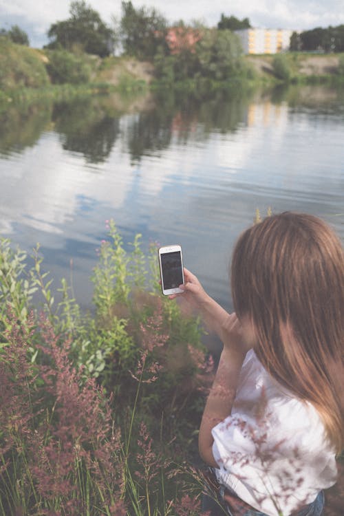 Back View of a Woman Taking Photo of a Lake Using Cellphone