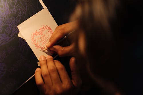 Close-Up Shot of a Person Writing on a White Paper Using a Colored Pencil