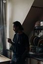 男人在柔和的自然光下靠近厨房窗户吸烟，陷入沉思